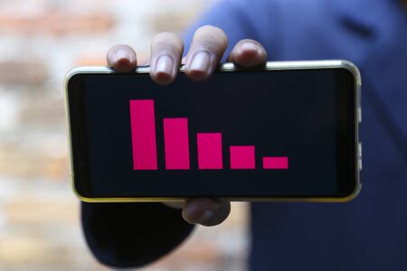 attractive hands showing decrease graph on a smart phoneの写真素材