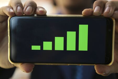 attractive hands showing profit graph on a smart phoneの写真素材
