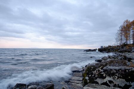 Beautiful waves on the lake, frozen fishermen in the backgroundの写真素材