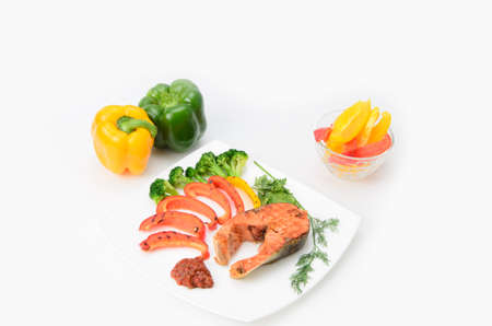 Grilled red fish with sauce, broccoli, parsley and dill  on a white plateの写真素材