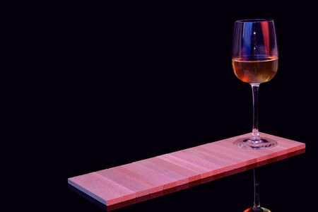 A glass of white wine on a black background on a wooden standの写真素材