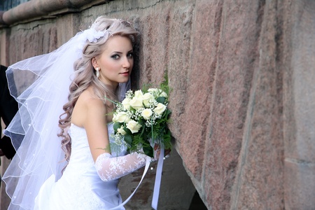 bride with  wedding bouquet Against  stone wall の写真素材