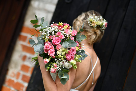 Bride holding a wedding bouquet of pink and white roses in her handsの写真素材