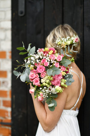 Bride holding a wedding bouquet of pink roses and eucalyptusの写真素材