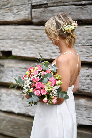 Bride with a bouquet of flowers in front of the wooden wallの写真素材