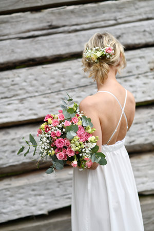 Bride with a bouquet of flowers on the background of a wooden wallの写真素材