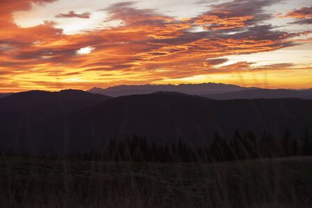 Autumn sunrise over Tatra Mountains national park in Poland. Panoramic breathtaking photo. Tatras in the background. Hills and trees in the foreground. Burning sky with clouds over the mountains.の写真素材