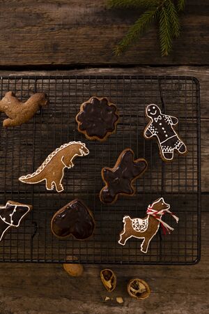 Homemade gingerbread in various shapes on an black grille on old wooden background.の写真素材