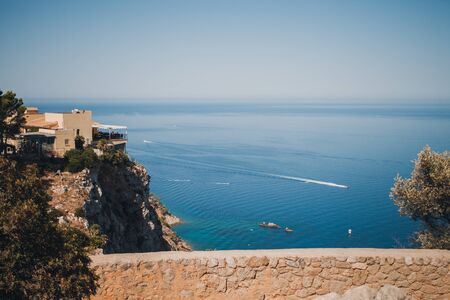 Hilly coast of Majorca. in the background a small boats on the sea. in the foreground building on a hill overlooking the sea. summer scenery, calm water. Selective focusの写真素材