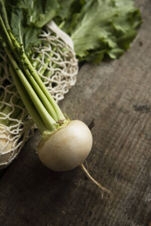 rustic organic turnips with fresh green tops and roots on genuine wood background. vegetarian food,...