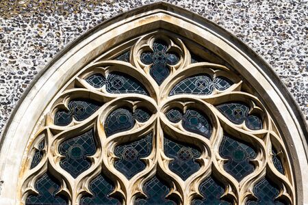 Carved sandstone window with stained glass seen from the outside of a medieval church in Englandの写真素材