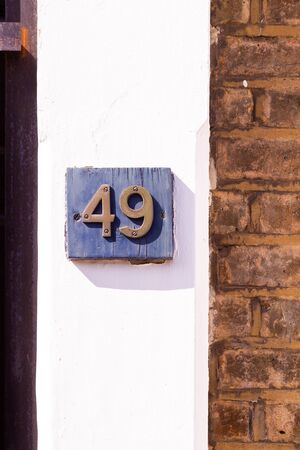 House number 49 on a black plaque on a white wall