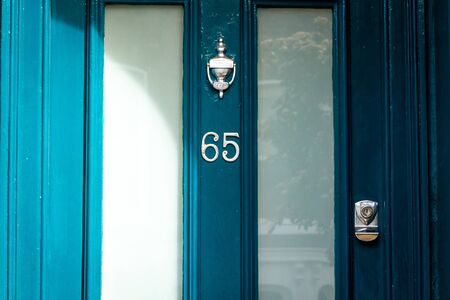 House number 65 on a blue wooden front door with large glass panelsの写真素材