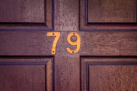 House number 79 on a dark varnished wooden front door