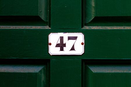 House number 47 on a white plaque on a dark green wooden front door