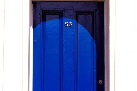 House number 53 on a royal blue wooden front door with vertical lines in London with white frameの写真素材