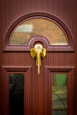 Elephant head door knocker with long trunk on a brown doorの写真素材