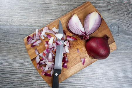Red onion on wooden board with knifeの写真素材