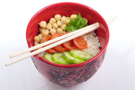 Rice with vegetable in red ceramic bowl with sticksの写真素材