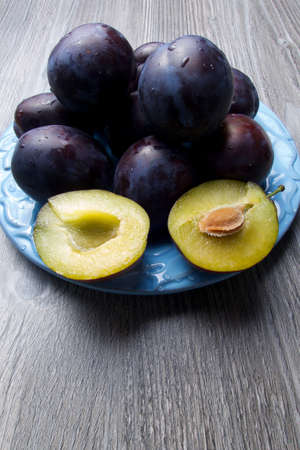 Purple fresh raw plums on blue ceramic plateの写真素材