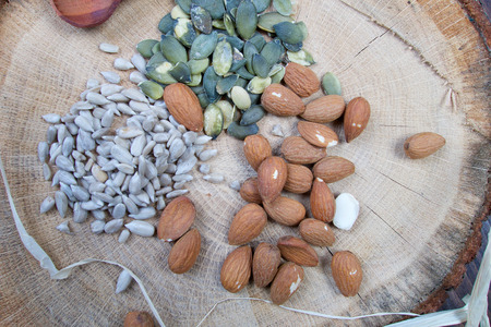 Almond, sunflower and pumpkin healthy seeds on wooden board with patternの写真素材