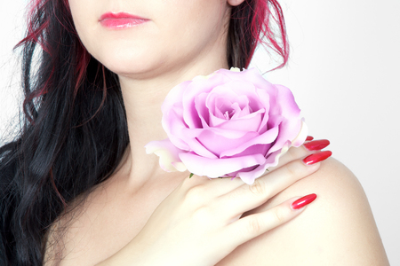 Beautiful woman with rose in pink lightの写真素材