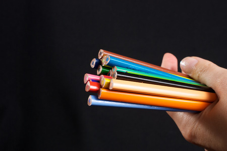 Business concepts: colourful pencils in the hand on black backgroundの写真素材