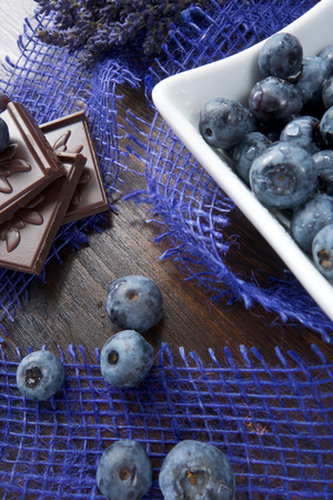 Blueberries and chocolate with lavender and spoon on wooden boardの写真素材