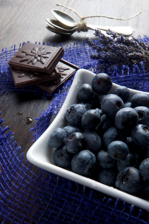 Blueberries and chocolate with lavender and spoon on wooden boardの写真素材