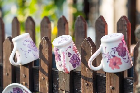 DIY concept. Ceramic handmade decorative glazed dishes on fence...