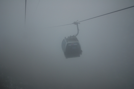 Fuzzy man walking on hanging bridge vanishing in fog. Focus on middle of bridge.の写真素材