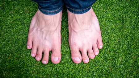 pair of bare feet heathy a man standing on soft refreshing green grasses lawn yard with copy spcae.