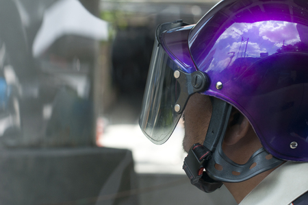 Side view of asian man wearing glossy purple helmet while riding motorbike in cityの写真素材