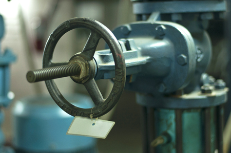 Close up hand wheel of brass gate valve with white tag label in building pipe systemの写真素材