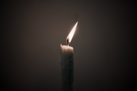 Yellow fire on white candle among dark space, one light and hope concept