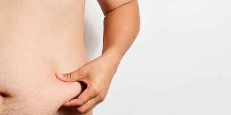 sian man pinch his belly abdomen isolated on light grey background, fat guy grab tummy. Overweight...