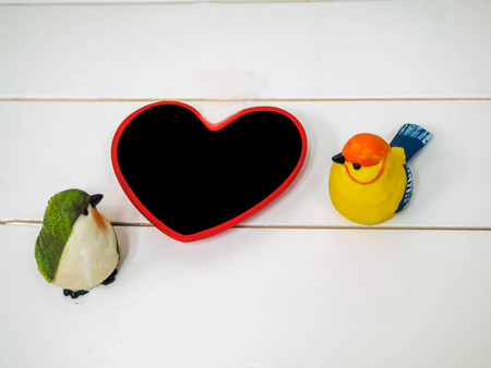 bird dolls made of stucco on white chair background with small board heart , black space for insert text or imageの写真素材