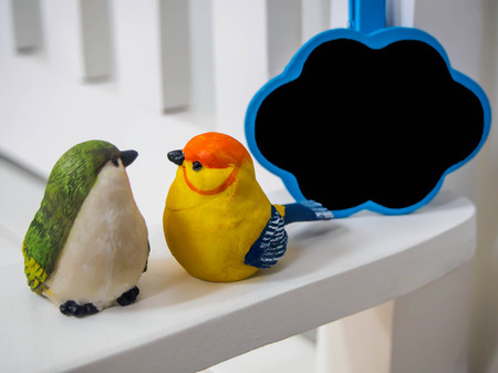 bird dolls made of stucco on white chair background with small board cloud , black space for insert...