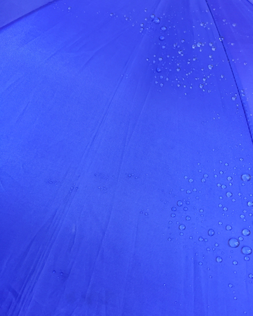 close up texture of rain drop on blue umbrella for backgroundの写真素材