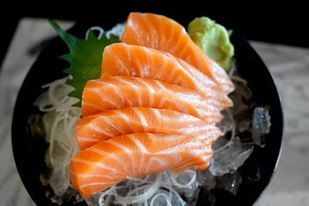 Raw salmon slice or salmon sashimi in Japanese style fresh serve on ice with fresh wasabi photo in  indoor low lighting.の写真素材