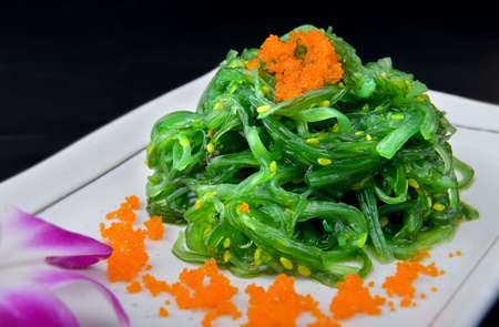 Japanese seaweed salad top with fish roes set on white plate with studio lighting.の写真素材