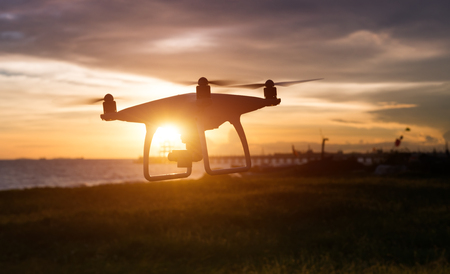 Silhouette of flying drone in sunset low lighting time.