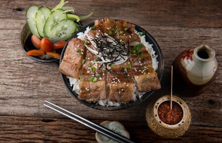Grilled slice pork with charcoal flame set on rice bowl in Japanese style butadon ready to serve.の写真素材