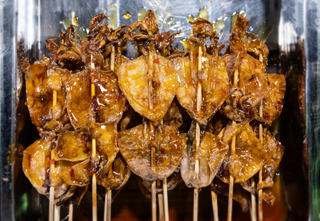 Dried squids in skewer street food with night market low lighting.