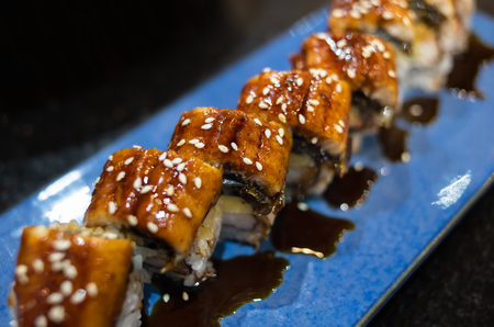 Japanese unagi eel grilled sushi maki roll cutting with indoor low and dark lighting in low focus.の写真素材