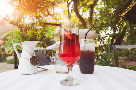 Ice cold berry fruit tea drink and ice coffee with outdoor sunset lighting.の写真素材