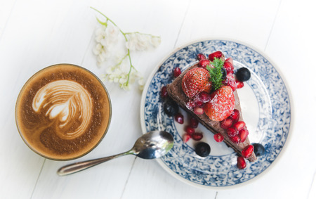 Chocolate cake topping with strawberry and berry fruits serve in old style plate in outdoor low lighting.の写真素材