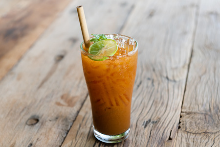 Ice cold sweet lemon tea drink  on the wooden table with outdoor sun lighting.