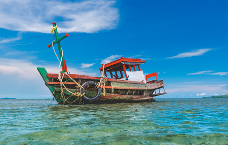 Fishery wooden boat at the shore seascape with blue sky and cloud.の写真素材
