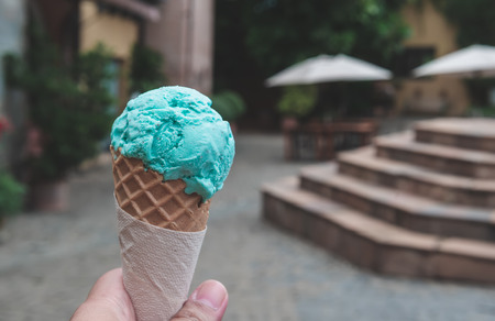 Blue ice cream in crispy cone with hand holding in oldtown background.の写真素材